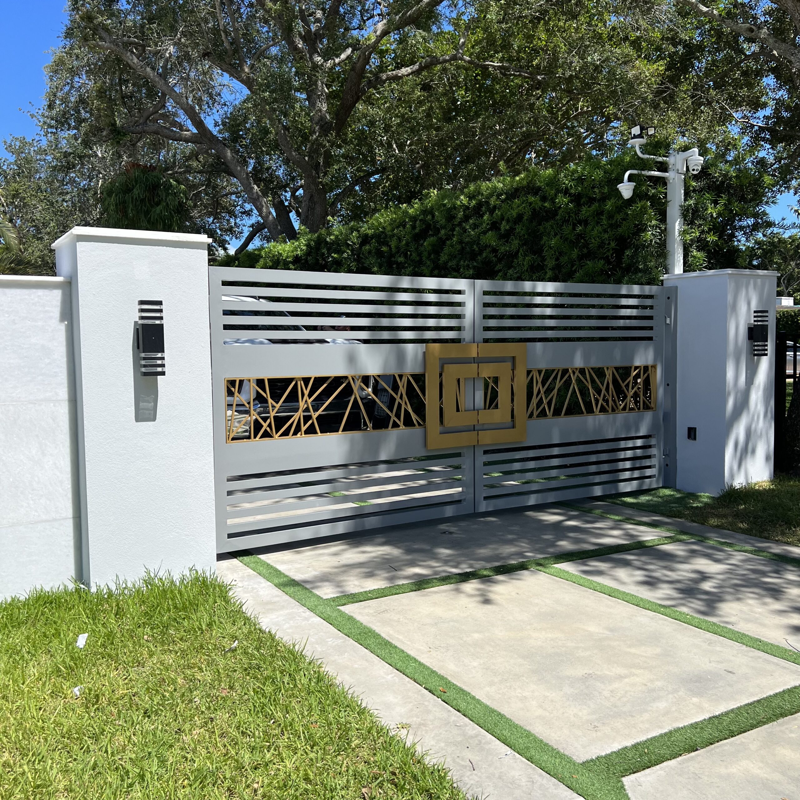 Modern gray & gold driveway gate with geometric design.